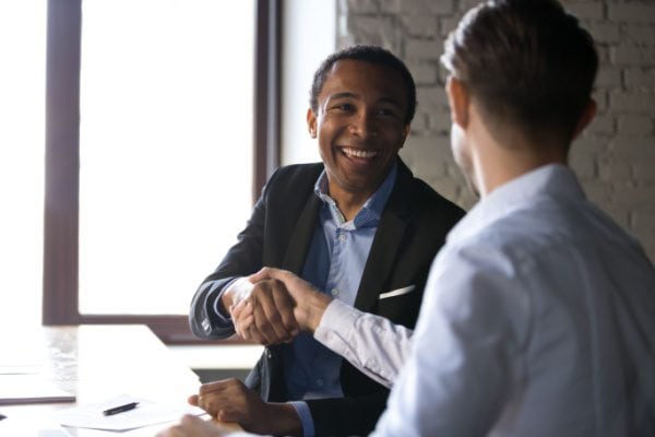 two men shaking hands at a table