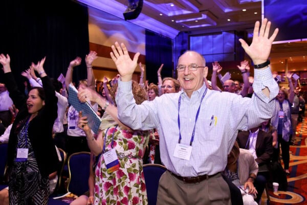 ICF Converge 2017 attendees standing with their hands raised, celebrating joyfully during the conference.