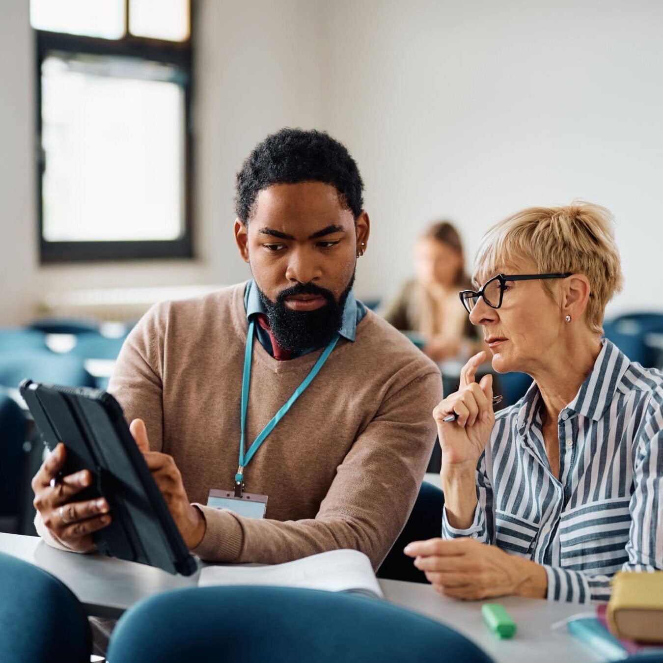 A man and a woman look at a tablet in an educational setting.