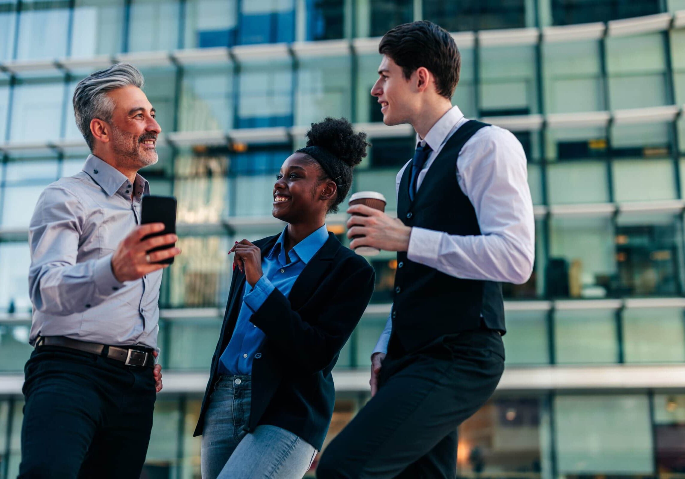 A few professional workers are taking a break outside, chatting and enjoying some coffee.