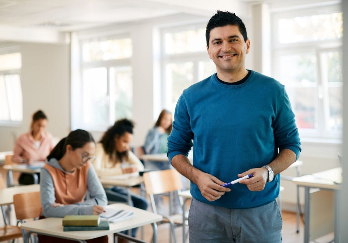 Teacher stands at front of classroom filled with adults