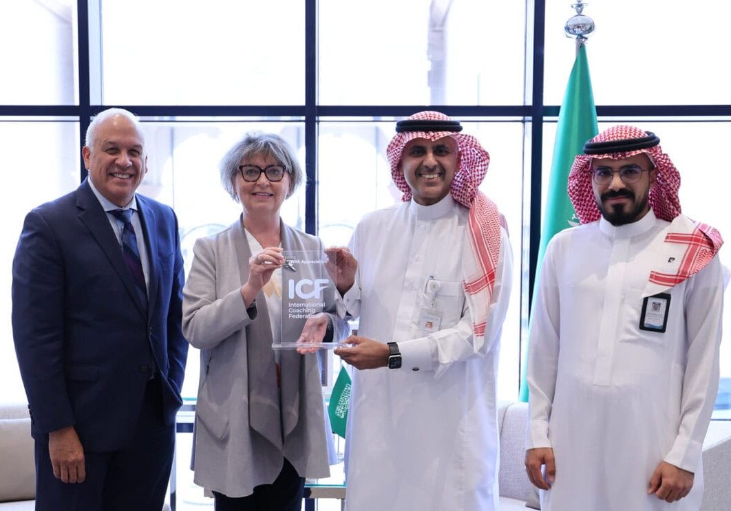 ICF CEO and a senior leader from the Saudi Food and Drug Authority smiling together while jointly holding a plaque, symbolizing a new partnership to promote coaching and professional development across the Middle East.