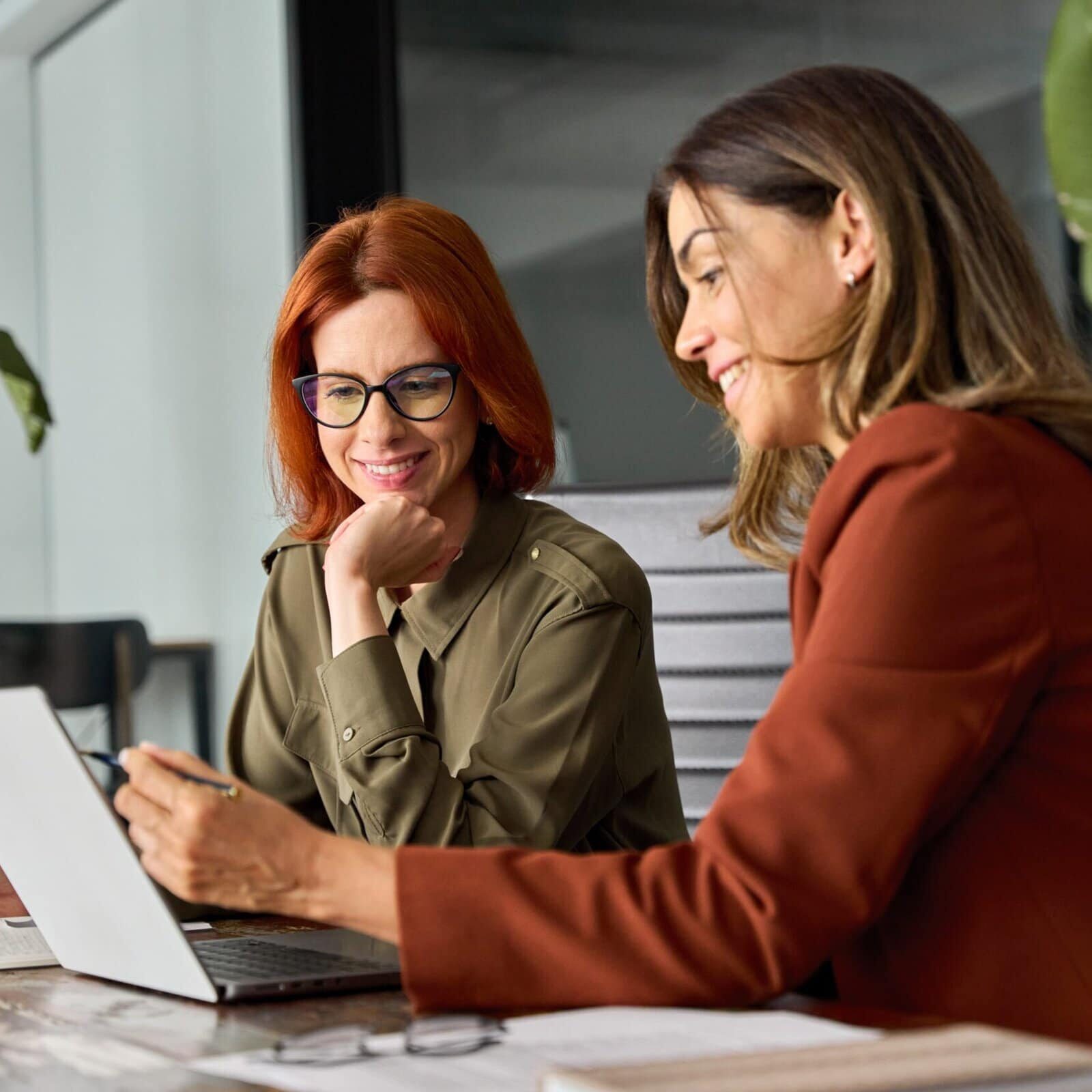 Two woman review the BDS information in an office setting on a laptop